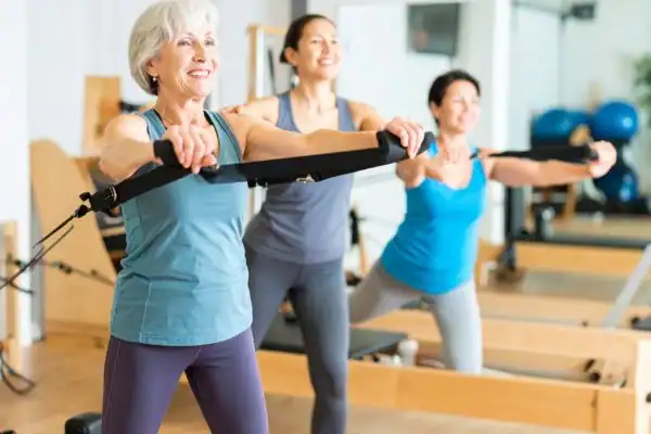 Toning Arms After 60: Empowering Womens Fitness Through Effective Weight Training 2 older woman doing weight training Weymouth and resistance in the gym to tone upper arms